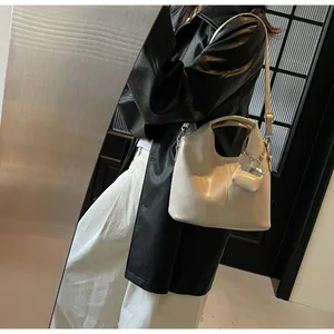 Detail of off-white vintage tote bag featuring vertical stitching and a mini charm bag
