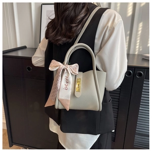 Détail d'un sac seau en cuir grainé avec foulard en soie et fermoir rotatif doré