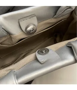 Macro shot of silver leather bucket bag featuring metal magnetic clasp and chevron lining