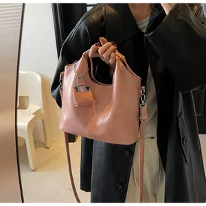 Detail of pink faux leather tote bag showing side metal chain lock charm and texture