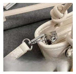 Detailed close-up of premium silver metal hardware and white lychee texture leather strap