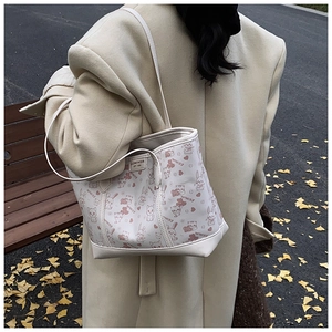 Outdoor lifestyle shot of a large beige tote bag with cute animal prints and leather patch