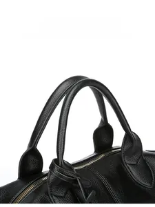 Close-up of black leather tote bag featuring reinforced handles and gold metal zipper