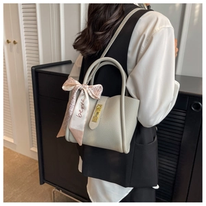 Sac seau en cuir grainé gris avec détail foulard en soie porté par un mannequin chic