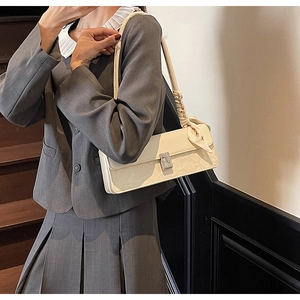 Detail of cream leather square bag featuring geometric embossing and floral silk scarf
