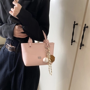 Detailed shot of pink leather mini tote with baseball charm and metal logo emblem
