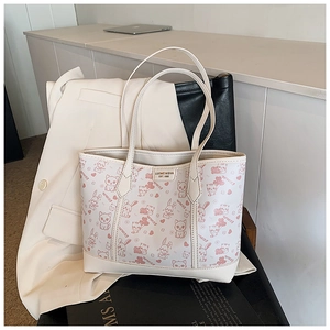 Detail of white tote bag with pink cat prints and premium stitching on leather surface
