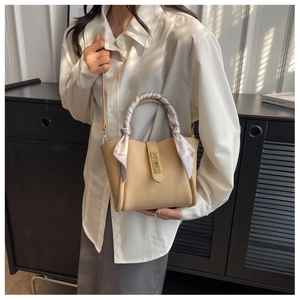 Détail du sac seau beige avec texture litchi, poignée en soie et fermoir doré chic