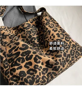Close-up of leopard print tote bag with soft fabric texture and red side label detail