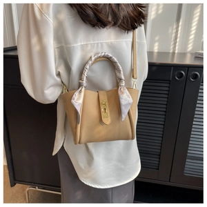 Détail de la poignée du sac seau avec un foulard en soie imprimé et un fermoir doré chic