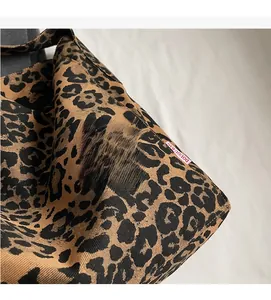 Detail of leopard print fabric tote bag with a woven texture and red brand side label