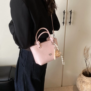Pink lychee grain leather crossbody bucket bag featuring a baseball charm detail