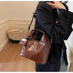 Close-up of vintage brown oil wax leather tote bag featuring a round handle and mini pouch