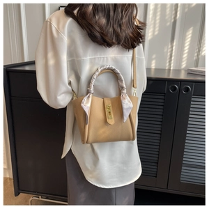 Détail d'un sac seau en cuir grainé kaki avec foulard en soie décoratif et fermoir métal