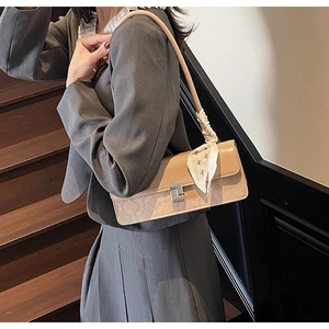 Detail of apricot square shoulder bag with geometric embossing and floral silk scarf accessory
