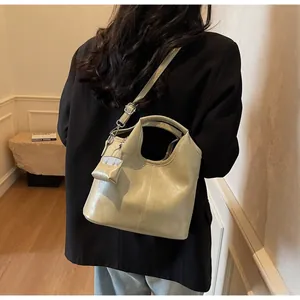 Detail view of beige tote bag with mini pouch pendant and adjustable strap on a model