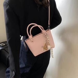 Detail of pink lychee leather bucket bag with baseball charms and knotted handles