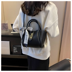 Détail du sac seau en cuir grainé noir avec foulard décoratif et fermoir doré