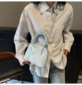 Détail du sac à main bleu clair avec cuir grainé et décoration de nœud en dentelle blanche