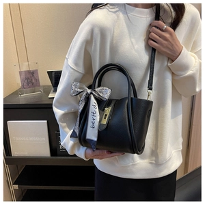 Détail du sac seau en cuir grainé noir avec foulard en soie imprimé et fermoir doré