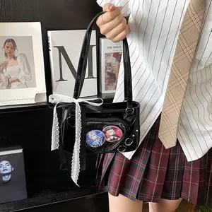 Detail of black ita bag with heart window showing anime badges and lace bow