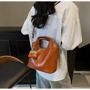 Brown oil skin tote bag side view with matching mini coin purse and adjustable strap