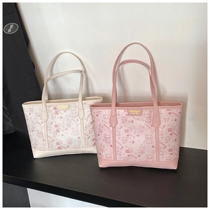 Detail of pink and beige tote bags with cartoon animal prints and gold logo plaques