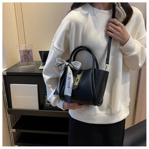 Détail du sac seau en cuir grainé noir avec boucle dorée et nœud en foulard de soie décoré