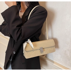 Detail of cream embossed leather handbag with diamond clasp and floral scarf accessory