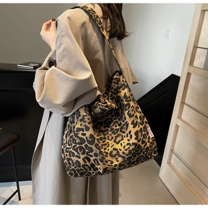 Close-up of leopard print tote bag with thick shoulder strap and red logo label