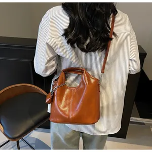 Detailed view of caramel brown leather bucket bag with top handle and crossbody strap