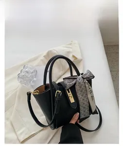 Détail du sac seau en cuir noir avec foulard en soie et fermoirs métalliques dorés