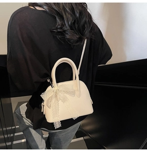 Vue détaillée d'un mini sac à main crème avec un nœud en dentelle porté par un mannequin