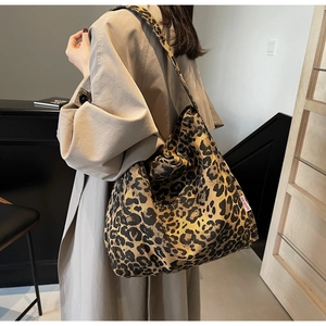 Detail of a large leopard print canvas tote bag worn with a stylish beige trench coat