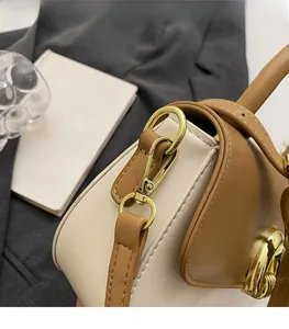 Detail of high-gloss gold hardware and caramel leather stitching on minimalist bag