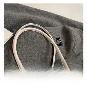 Detail view of thickened padded handle on a cream white leather tote bag with silver D-rings