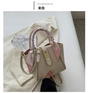 Détail du sac seau beige à texture grainée avec une poignée enroulée d'un foulard