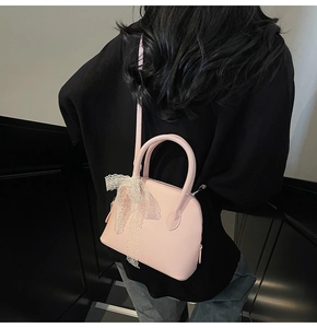 Sac à main rose avec nœud en dentelle blanche porté sur une tenue noire chic