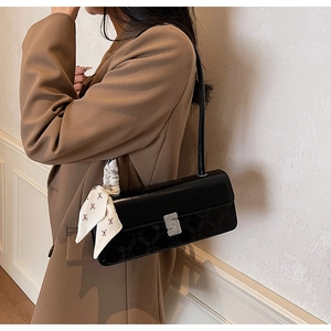 Detail of black leather shoulder bag with crystal buckle and decorative silk scarf
