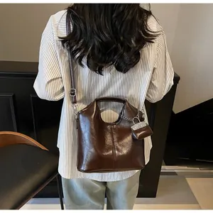 Detail of dark brown oil wax leather tote bag with silver chain and mini pouch