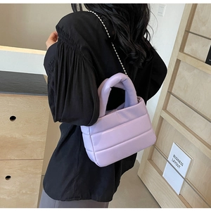 Detail of a purple quilted puffy bucket bag with silver ball chain and thick handle