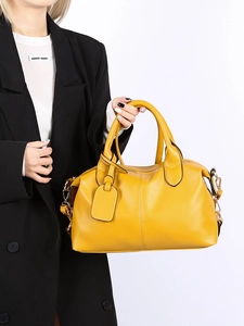 Detailed close-up of yellow pebbled leather handbag with double handles and metal hardware