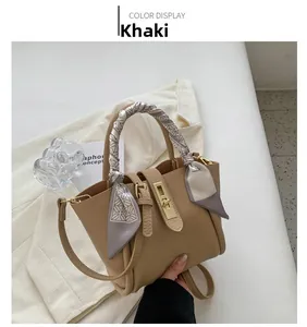Détail d'un sac seau en cuir kaki avec poignée en foulard de soie et fermoir doré