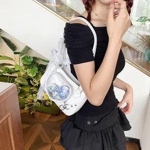 Close-up of white Ita bag with a heart-shaped transparent window and lace details