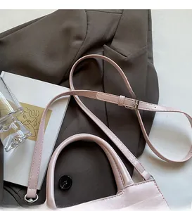 Detail of pink faux leather handbag showing crocodile texture and adjustable silver buckle strap