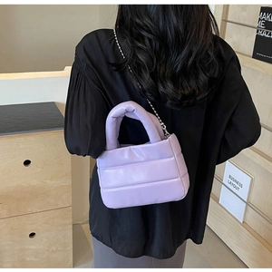 Detail of light purple quilted handbag with puffer texture and silver ball chain strap