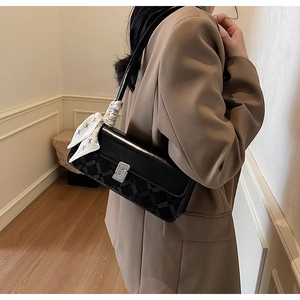Detail of black rectangular shoulder bag with geometric texture and silver S-shaped buckle
