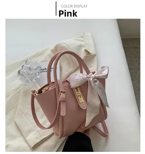 Sac seau rose en cuir avec foulard imprimé posé sur un blazer blanc