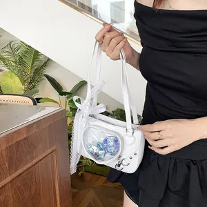 Detailed view of a white heart-shaped ita bag featuring lace bows and anime badges