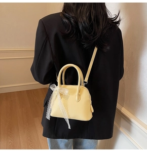 Détail d'un petit sac en cuir jaune clair avec nœud en dentelle blanche et bandoulière